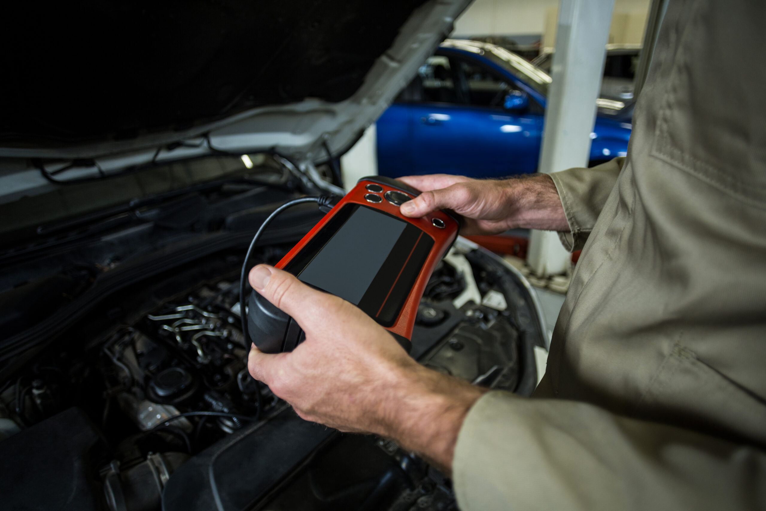 Hands of mechanic using a diagnostic tool in repair garage